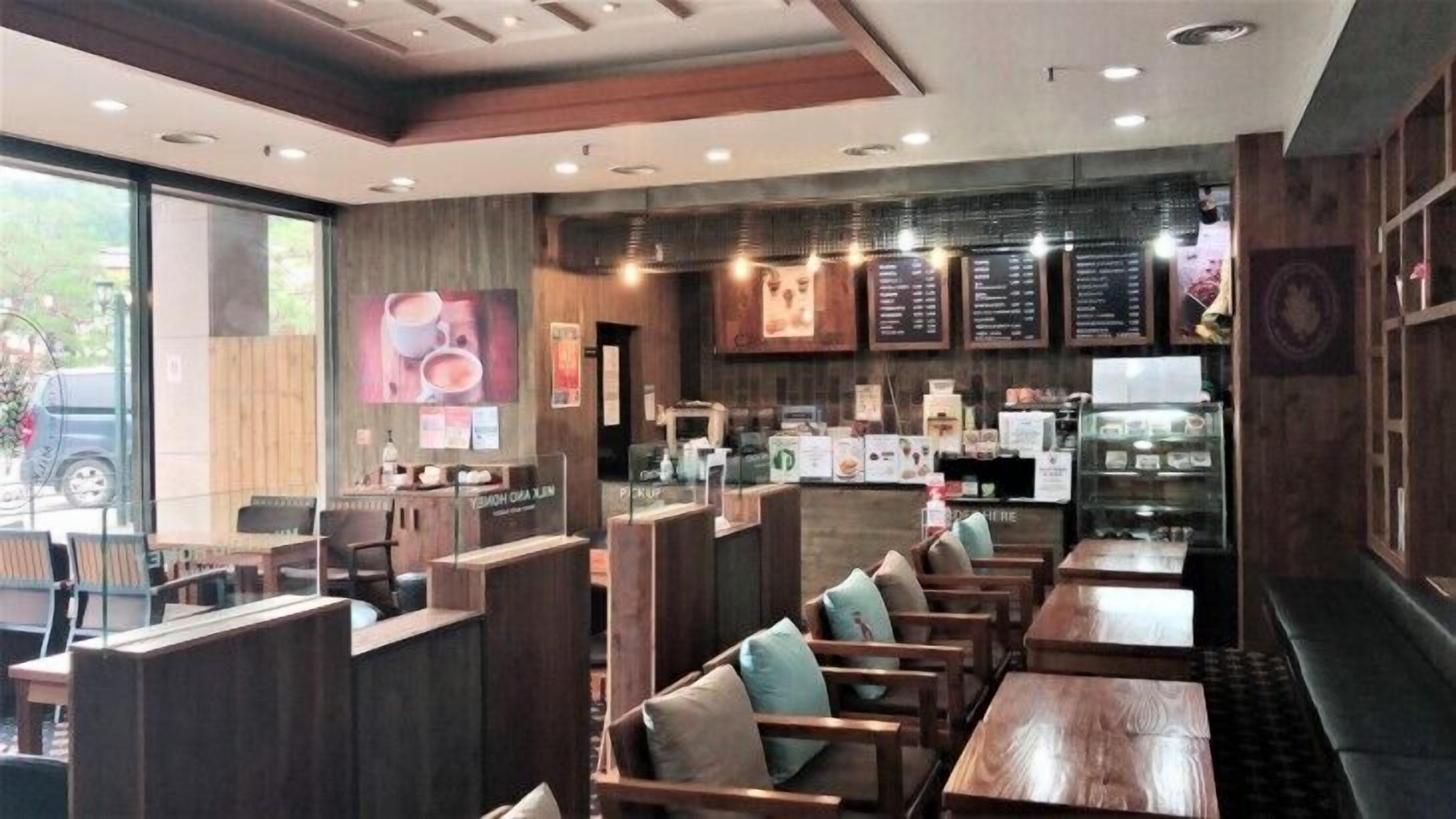 Interior de restaurante con mobiliario de madera, una barra y paneles con la carta.