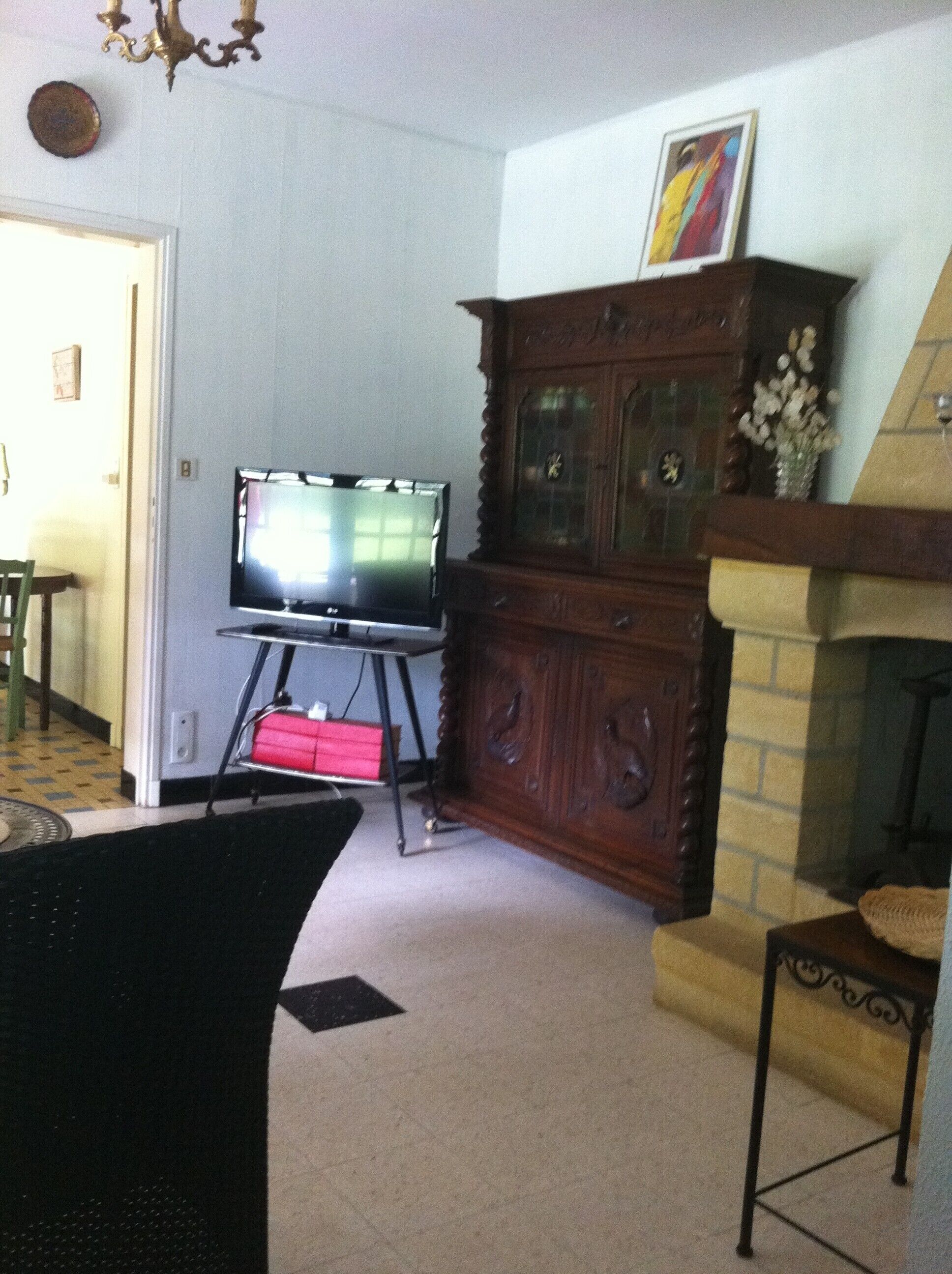 Un salon avec un téléviseur posé sur un meuble, une armoire en bois, une cheminée et un escalier.