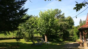 Een tuin met twee loungestoelen, een bijzettafeltje en een prieeltje.