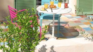 Une terrasse avec une table et des chaises, une petite plante et un sol carrelé.
