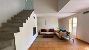 Un vaste espace de vie comprenant un escalier, un ensemble de canapés et une table basse.