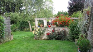 A well-maintained garden with a stone wall, various potted plants, and a wooden trellis. - Detached 3-star house in a village with shops (Sarrey)