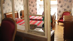 A room with a wooden bed, a red chair, a wooden table, and a window with a view of another room. - Detached 3-star house in a village with shops (Sarrey)