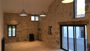 A spacious room with stone walls, large windows, and pendant lighting.