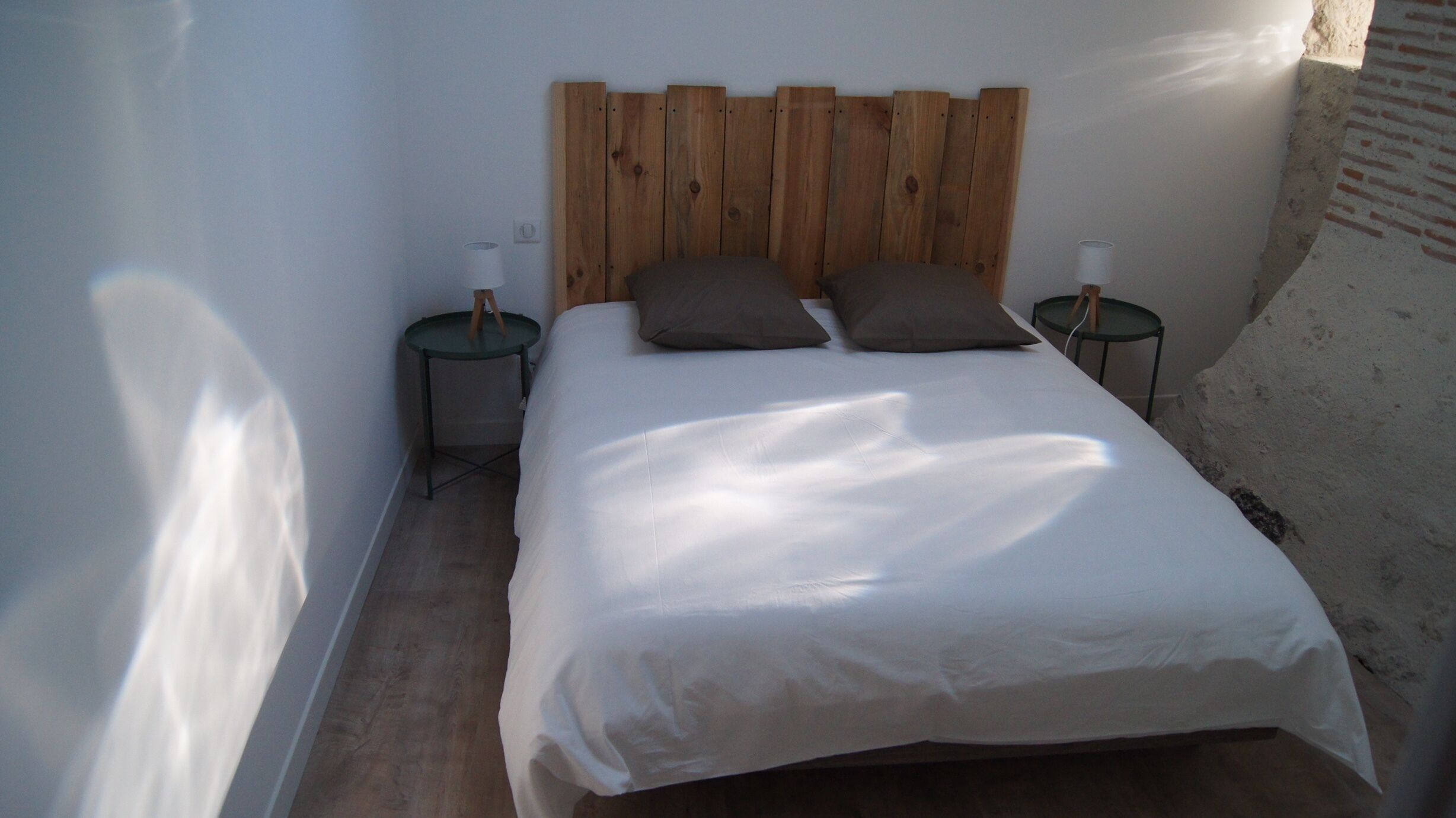 A bedroom with a wooden headboard, two bedside tables with lamps, and a large bed with white bedding.