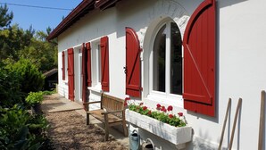 A white building with red shutters and a bench outside. - QUIET LANDAISE HOUSE ON THE EDGE OF A 3-STAR FOREST (Labenne)