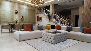 A spacious living room with a large sectional sofa, a tufted ottoman, and a dining area with a table and chairs. A staircase with decorative railings is visible in the background. - Superb villa with private heated swimming pool and gym. (Marrakech)