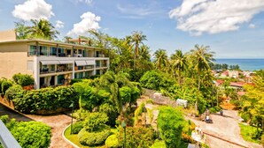 A modern hotel with a two-story structure, surrounded by lush greenery and palm trees, overlooking a coastal area. - Karon Butterfly Residence (Karon)