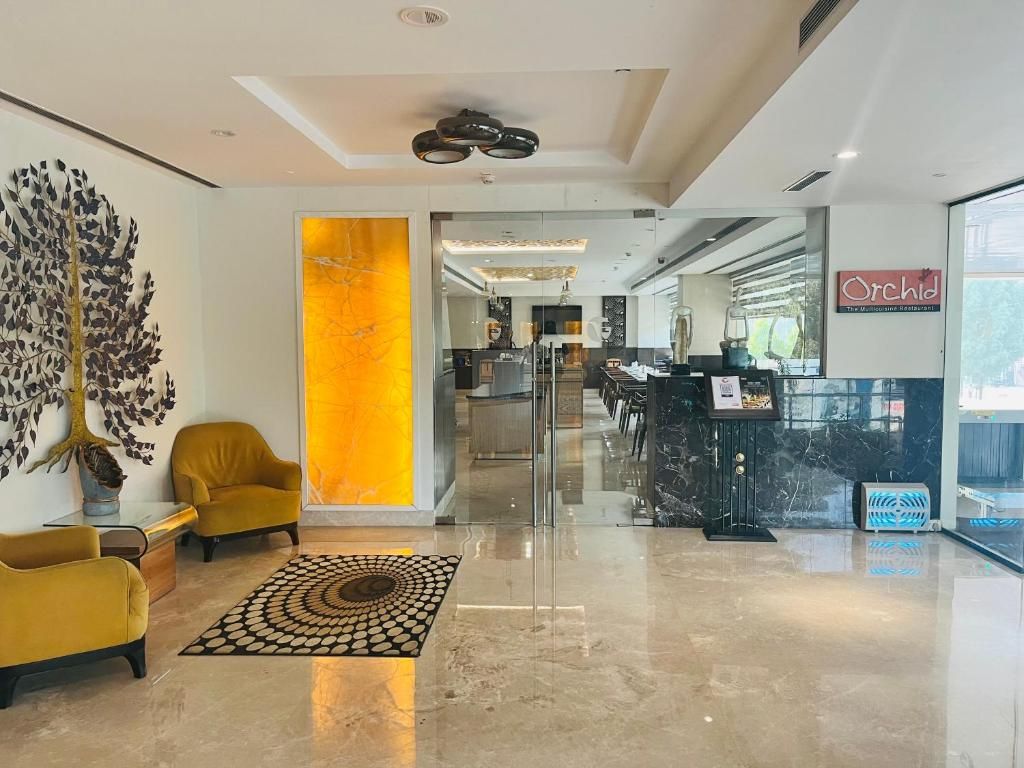 A modern hotel lobby with a reception desk, seating area, and a large decorative wall.