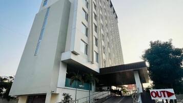 Entrada moderna de un hotel con una escalera que conduce al edificio principal, cielo despejado y un letrero que indica la salida.