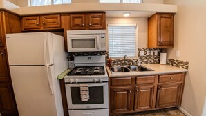 Una cocina compacta equipada con refrigerador, estufa, horno, microondas y pileta.