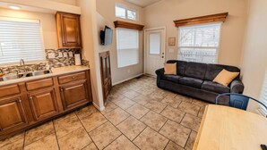 Una cocina amplia con armarios de madera y piso de baldosas, un sofá de cuero negro y un ventilador de techo.