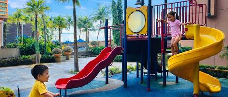 A children's play area with slides and a red toy car.