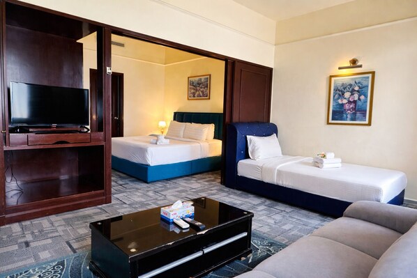 A hotel room with a TV, two beds, a sofa, and a coffee table. - KL Service Apartment at Times Square (Kuala Lumpur)