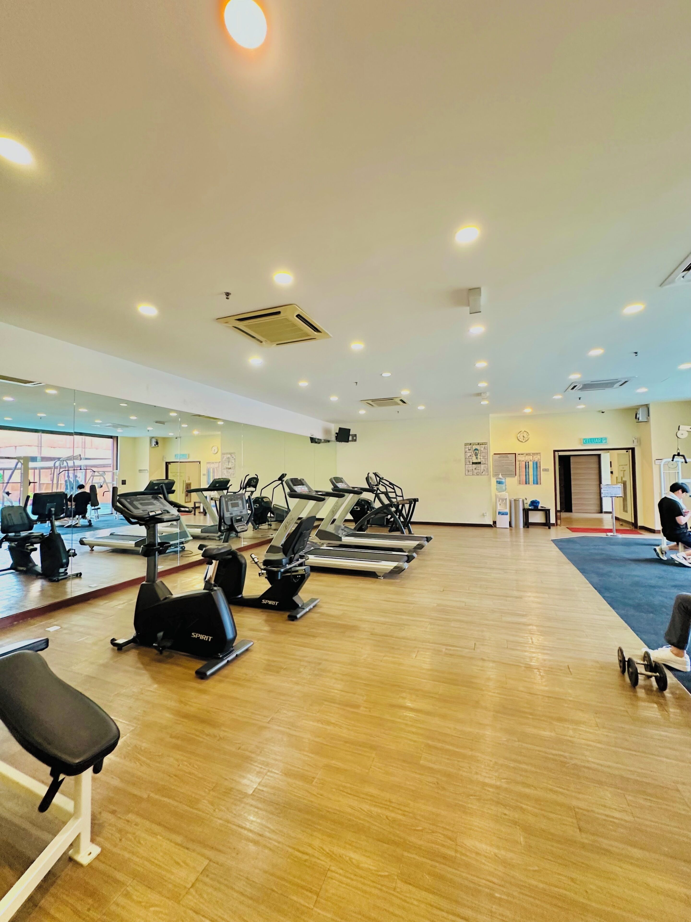 A gym with multiple treadmills, stationary bikes, and a mirrored wall.