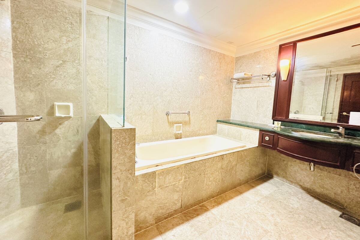 A modern bathroom with a glass shower enclosure, a freestanding bathtub, and a large mirror.