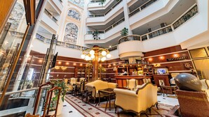 A multi-level hotel lobby with a bar area, seating, and a decorative clock. - Hotel Europe (Minsk)