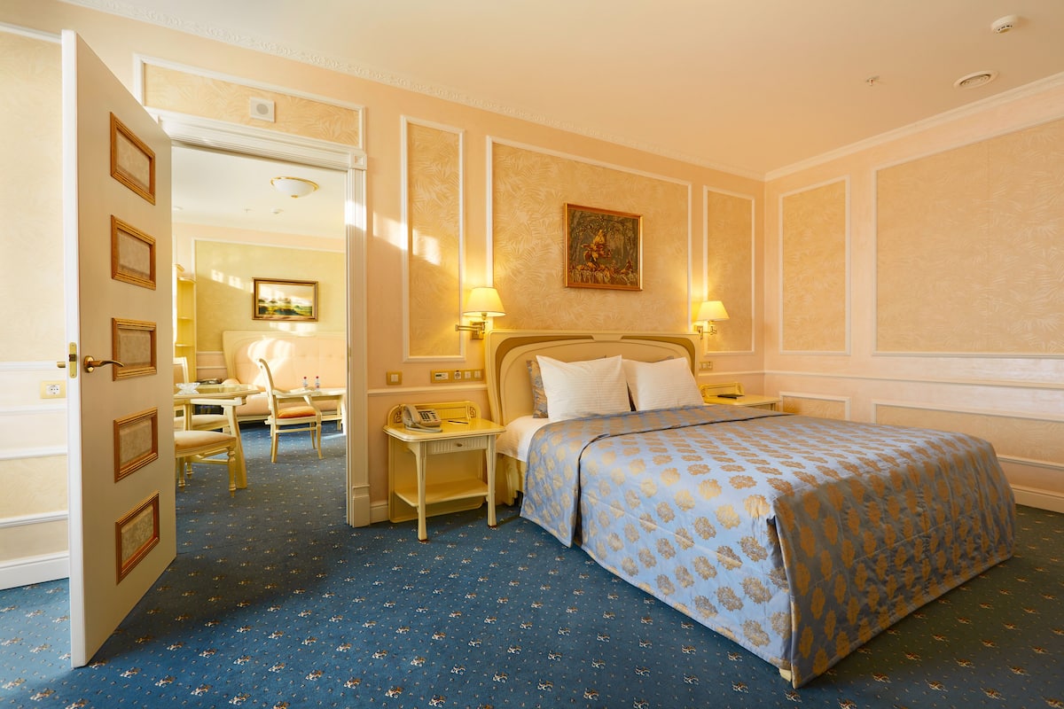 A hotel room with a bed, bedside tables, a desk, and a chair.