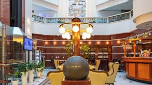 A lobby with a large chandelier, seating area, and a bar.
