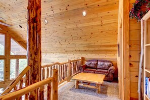 A wooden interior with a wooden staircase, a sofa, and a table. - Gorgeous 5-Star Chalet Mid-way Between Bryce & Zion - Read our reviews! (Alton)