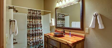 A bathroom with a wooden vanity, a large mirror, a shower curtain with animal prints, and a towel rack.