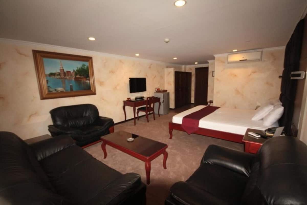Une chambre d’hôtel avec un lit, un bureau, une télévision et un tableau au mur.