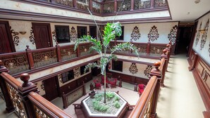 Um átrio com vários níveis, com grades elaboradas, um jardim vertical central e um candelabro.