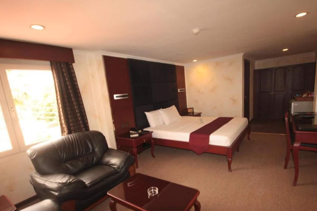 Une chambre d’hôtel comprenant un lit, un canapé en cuir, une table basse en bois et un bureau avec une chaise.
