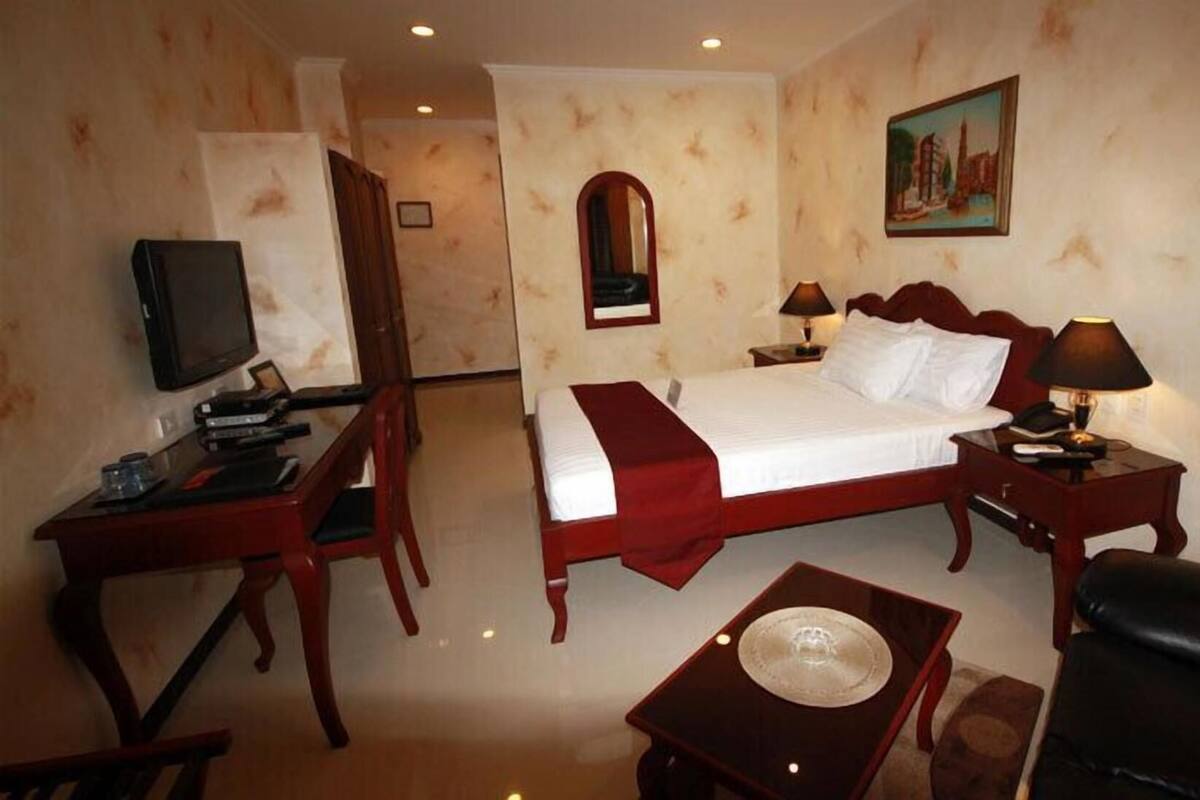 Une chambre d’hôtel avec un lit, un bureau, une chaise, une télévision et un tableau au mur.