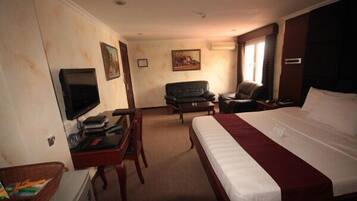 Een hotelkamer met een groot bed, een bureau met een televisie, een bank en een stoel.