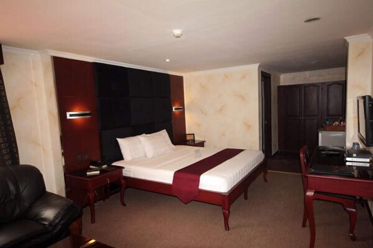 Une chambre d’hôtel avec un grand lit, un bureau avec une chaise, une télévision et une armoire.
