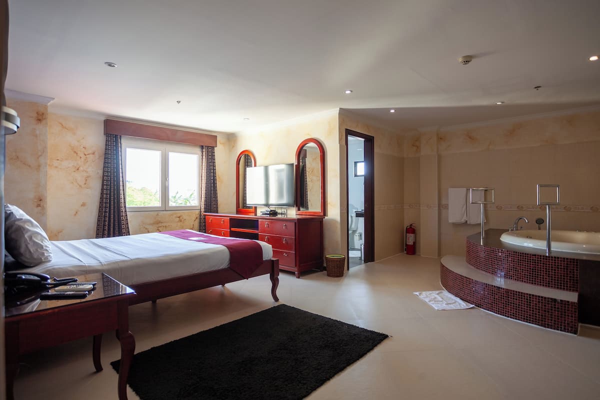Une chambre à coucher comprenant un lit, une commode et une salle de bain avec un lavabo et un miroir.