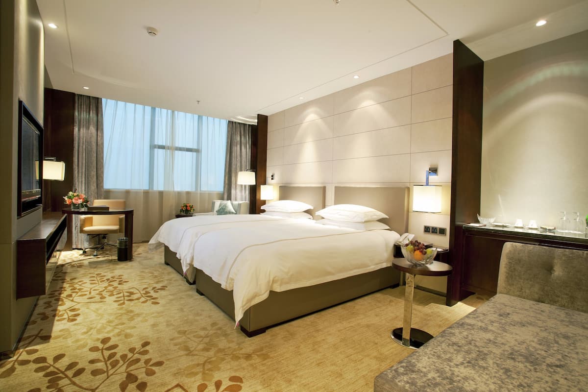 A hotel room with a large bed, bedside tables, a desk, and a seating area.