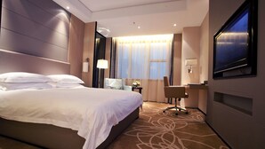 A hotel room with a large bed, a desk, a TV, and a window with curtains. - Winnerway Hotel (Dongguan)