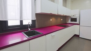 A modern kitchen with white cabinets, a pink countertop, a built-in oven, and a window with a white curtain. - NEW Luxurious Epicenter II Apartment:Free parking, Top location,Free A/C & Wi-Fi (Sevilla)