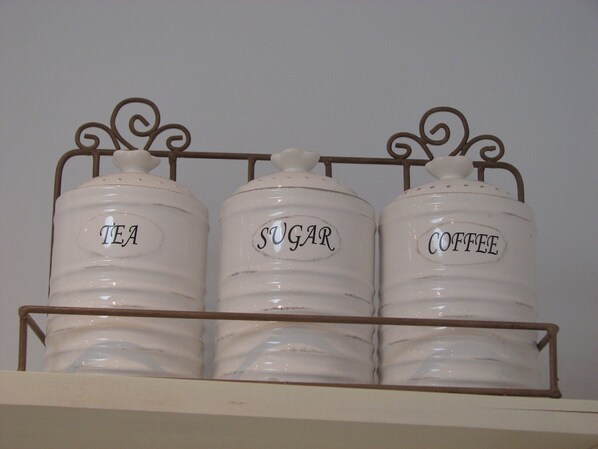 Three white containers labeled 'TEA,' 'SUGAR,' and 'COFFEE' on a metal rack. - Cosy, modern, quiet Apartment ideal for couples, no complex, sea view (Tías)
