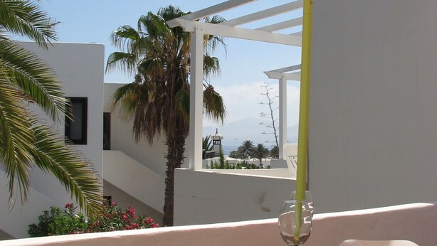 Ein Balkon mit Tisch, Stühlen und Sonnenschirm.