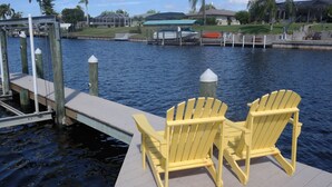 A dock with two yellow Adirondack chairs facing a calm body of water.