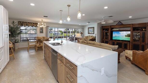 A spacious kitchen with a large island, wooden cabinets, and a built-in TV.