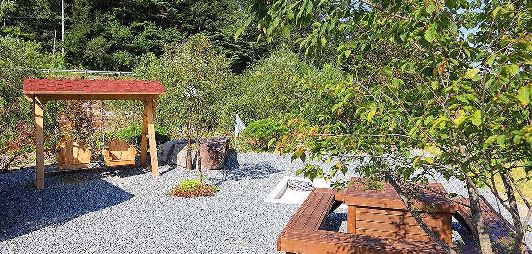 Une terrasse de jardin agrémentée d’une pergola en bois, de coins salon et de plantes en pot.