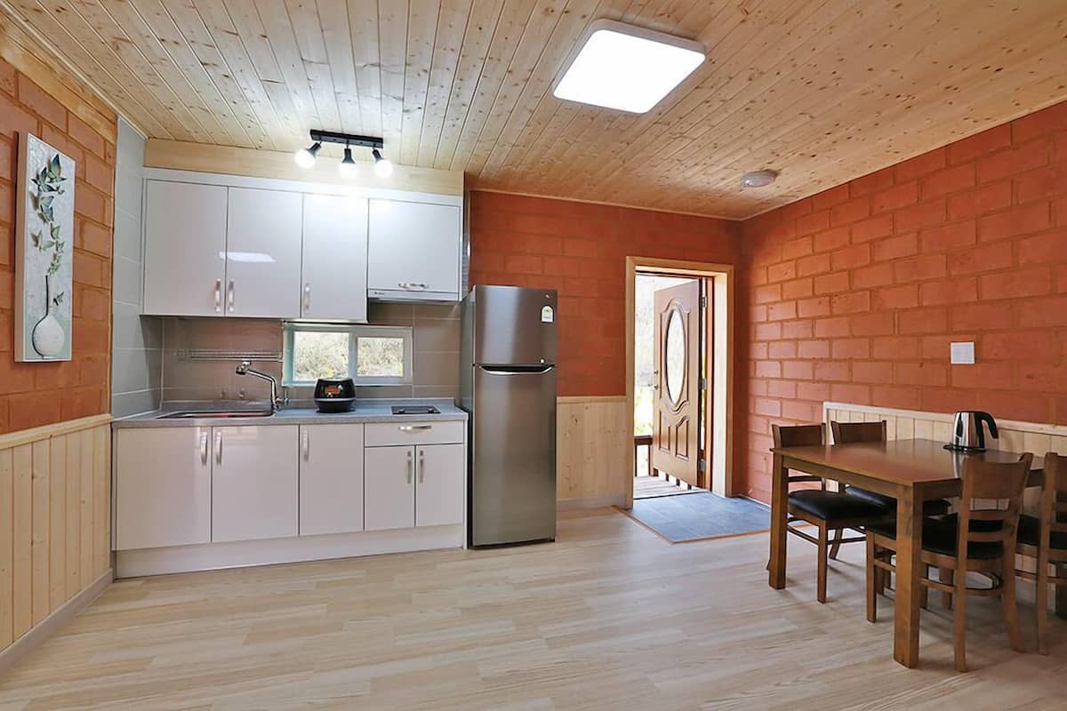 A kitchen with white cabinets, a stainless steel refrigerator, and a dining table with chairs.