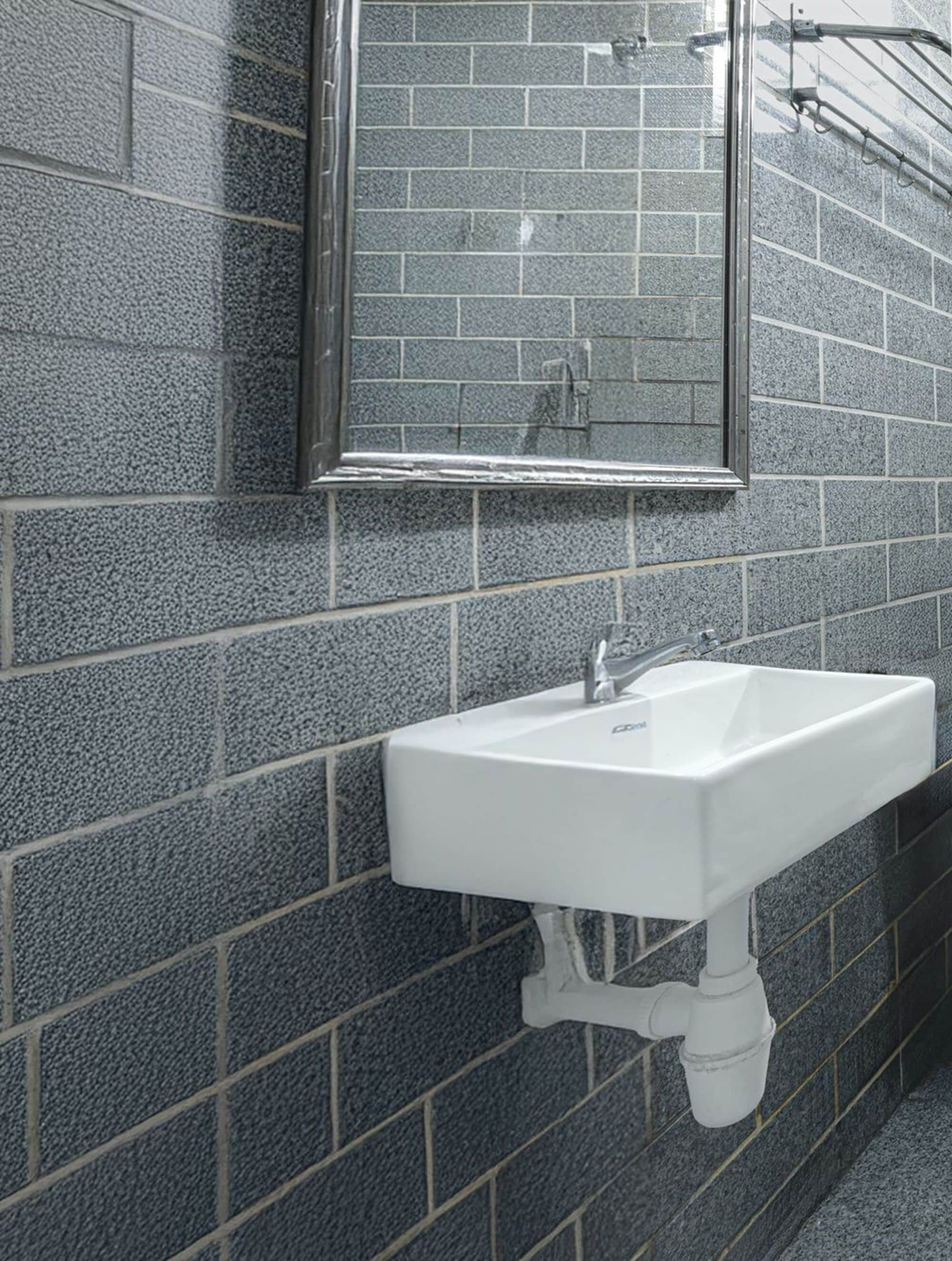 A bathroom with a white sink, a mirror, and a tiled wall.