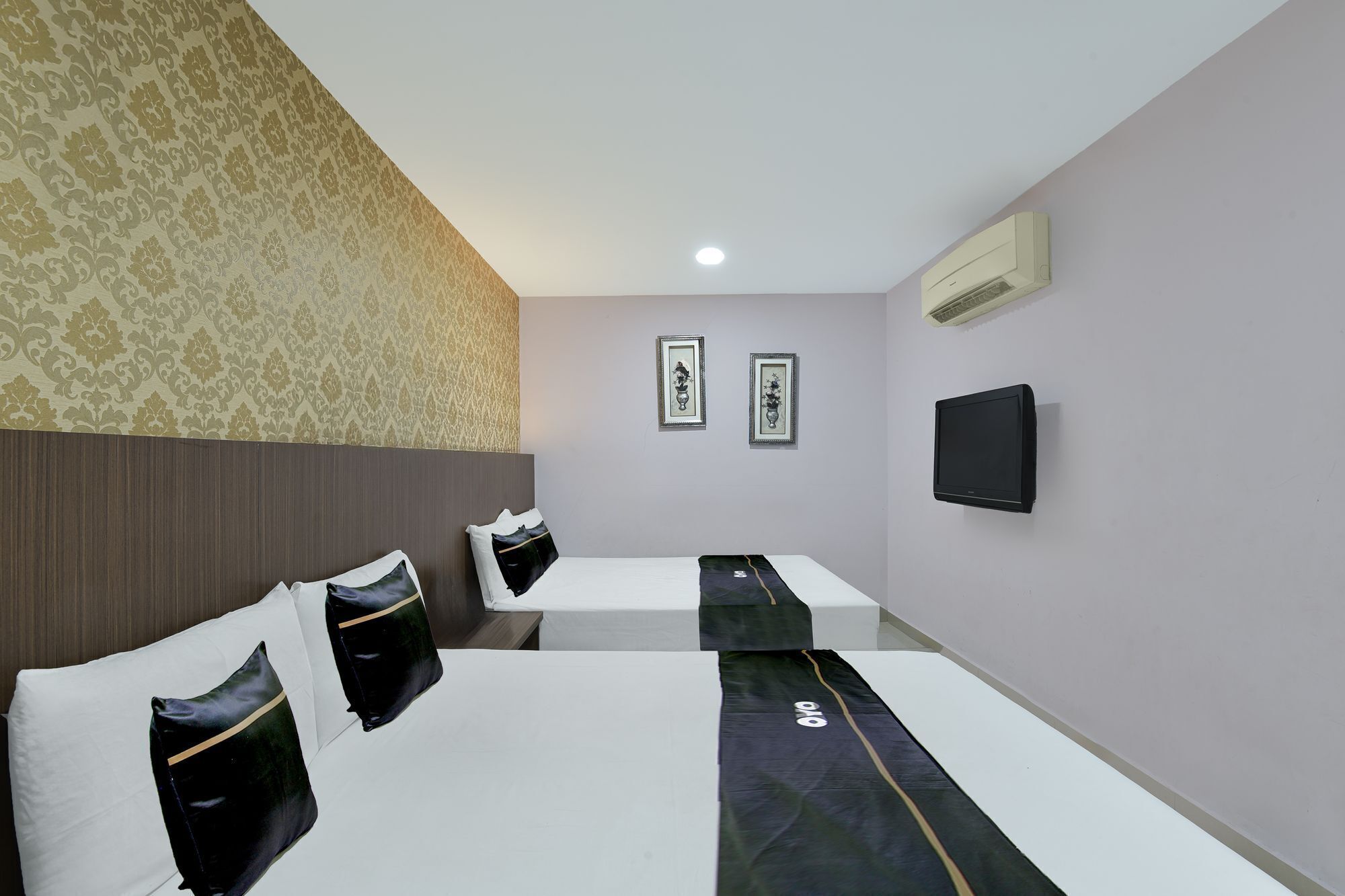 A hotel room with two beds, a flat-screen TV, and two framed artworks on the wall.