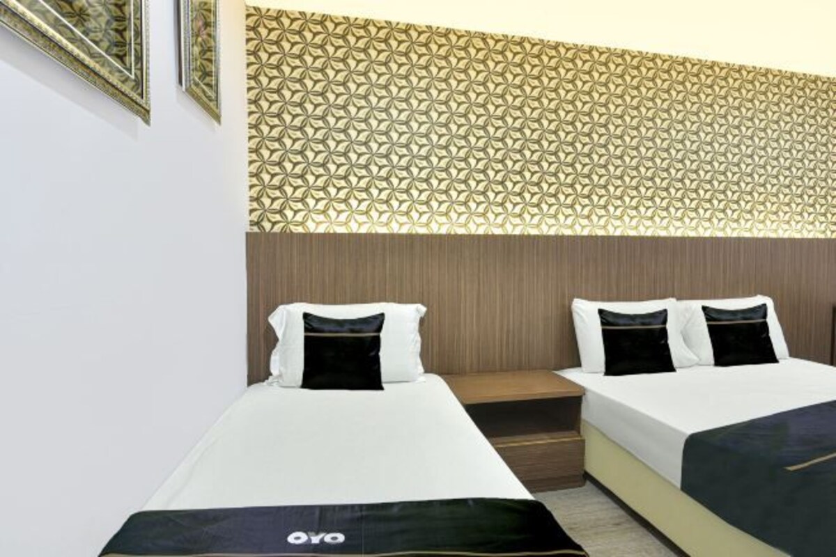 A hotel room with two beds, a patterned wall, and a wooden headboard.