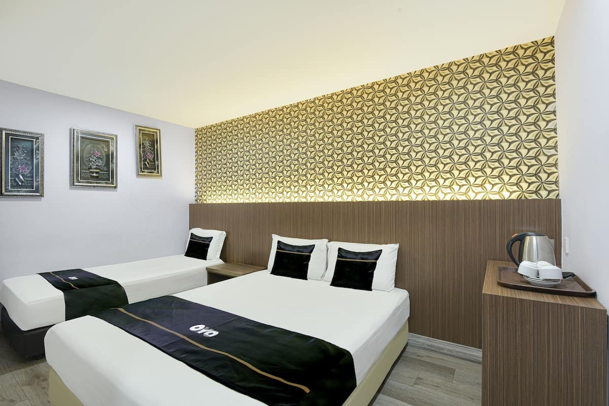 A hotel room with two beds, a wooden headboard, a patterned wall, and a small table with a kettle.