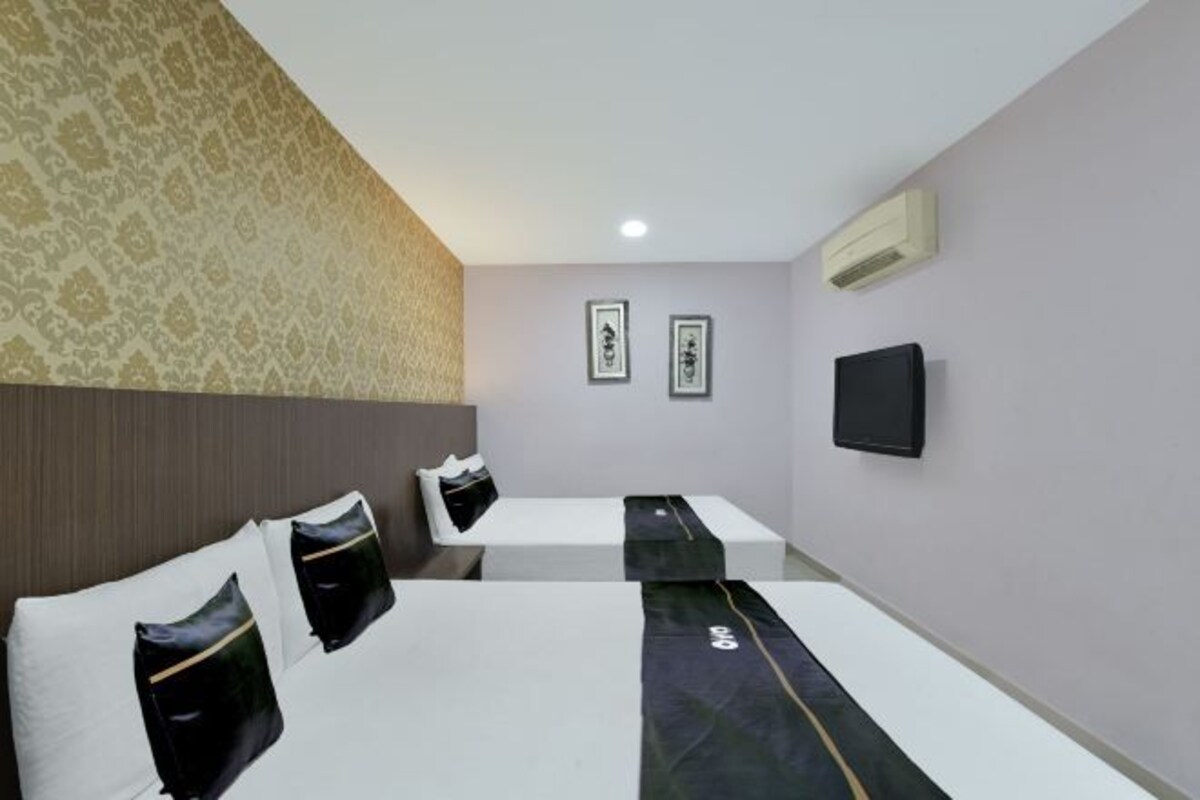 A hotel room with two beds, a flat-screen TV, and an air conditioning unit.