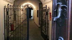 A corridor with ornate metal gates and a wooden door with a metal handle. - Piazza Collegiata Bellinzona (Bellinzona)