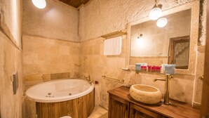 A bathroom with a freestanding bathtub, a wooden vanity, a large mirror, and a towel rack. - Charming Cave Hotel (Nevsehir)