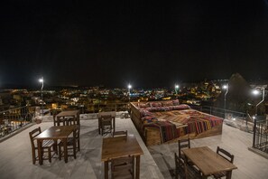 A rooftop terrace with wooden furniture and a colorful blanket. - Charming Cave Hotel (Nevsehir)