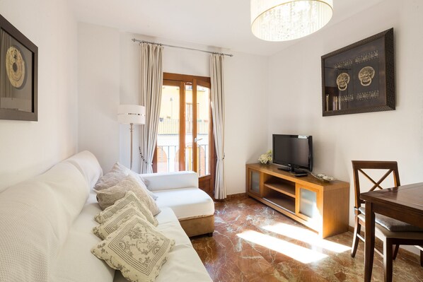 A modern living room with a sofa, TV, and wooden side table.